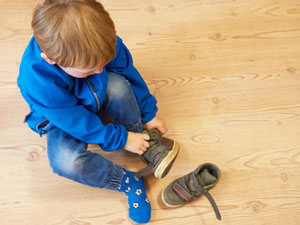 Ein Kind zieht sich selbst die Schuhe an