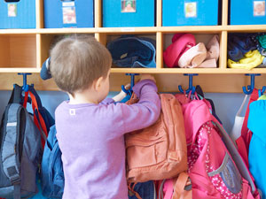 Kind hängt seinen Rucksack an die Garderobe